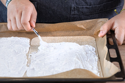 Creme vega auf dem veganen Flammkuchenteig verteilen