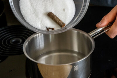 Zucker, Nelken und Zimtstange ins Wasser geben