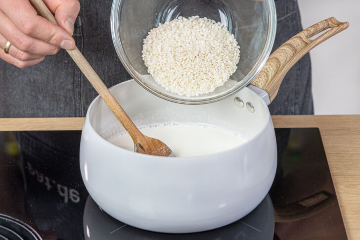 Milchreis zur Milch in den Topf geben