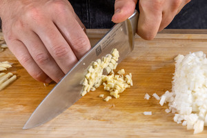 Zwiebel und Knoblauch in kleine Würfel schneiden
