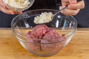 Hälfte der Zwiebel- und Knoblauchwürfel zum Hackfleisch geben