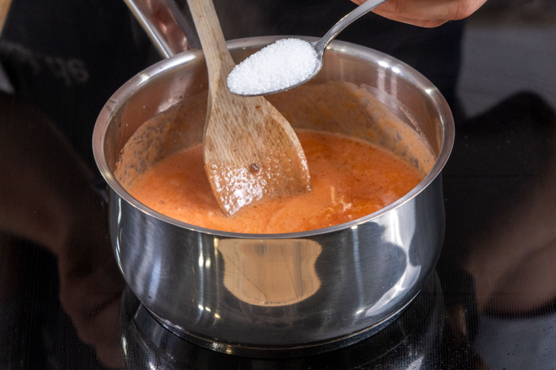 Zucker zu der Tomatensauce für den Hähnchenbrust-Auflauf ohne braten geben