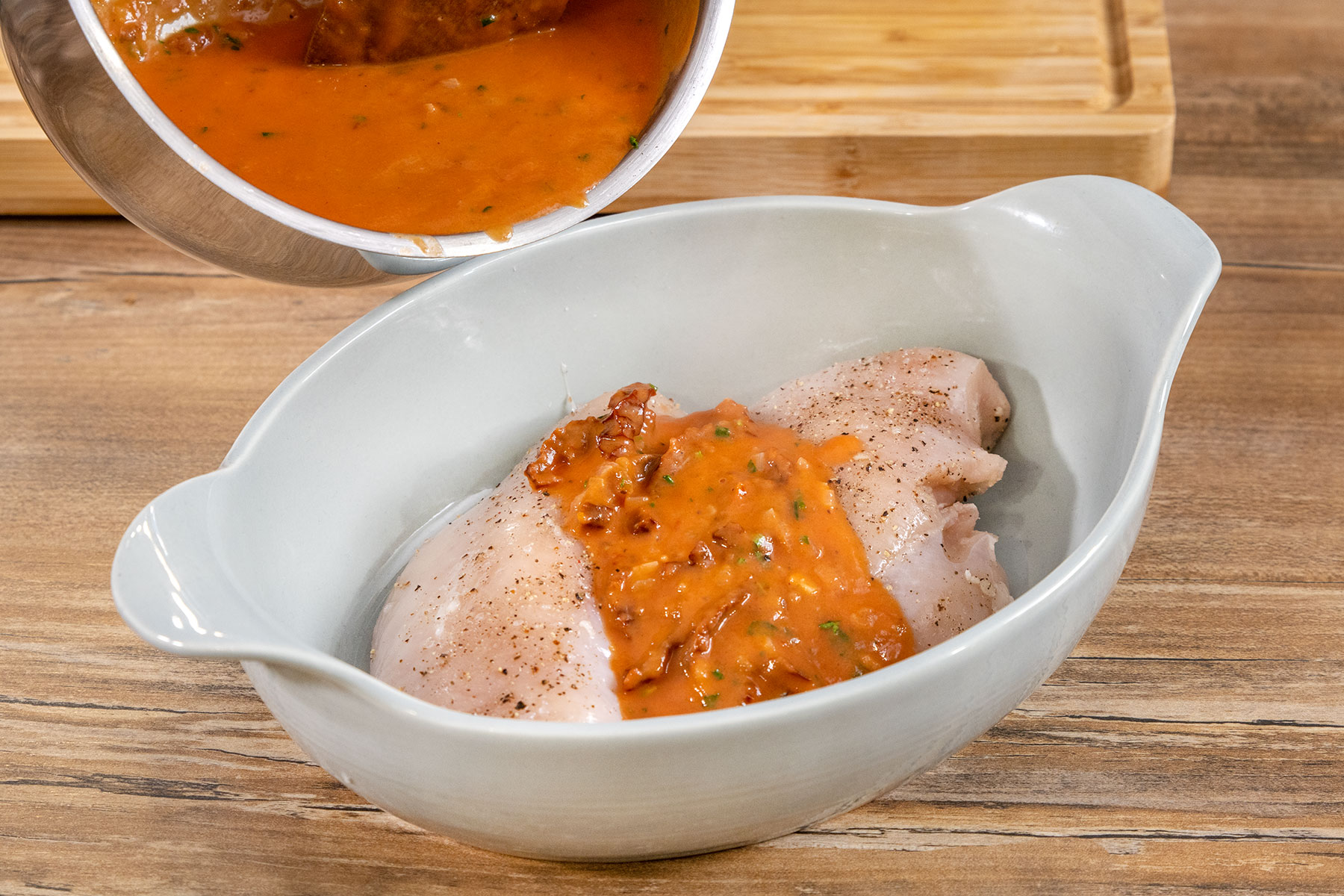 Tomatensauce über das Hähnchen in die Auflaufform gießen