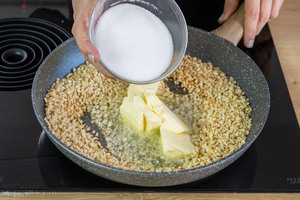 Butter und Zucker zu den Mandeln geben