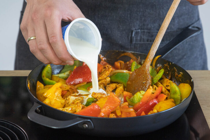 Sahne zum Paprika-Hähnchen-Geschnetzeltem dazugeben