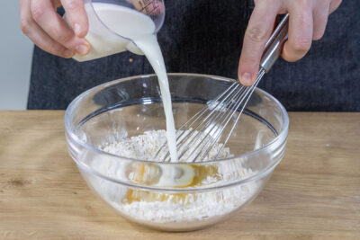 Ei und Milch in die Schüssel geben