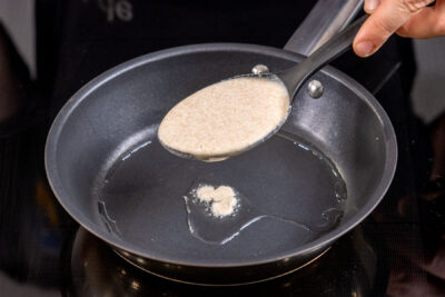 Pfannkuchenteig ohne Ei, Milch und Zucker in die Pfanne geben