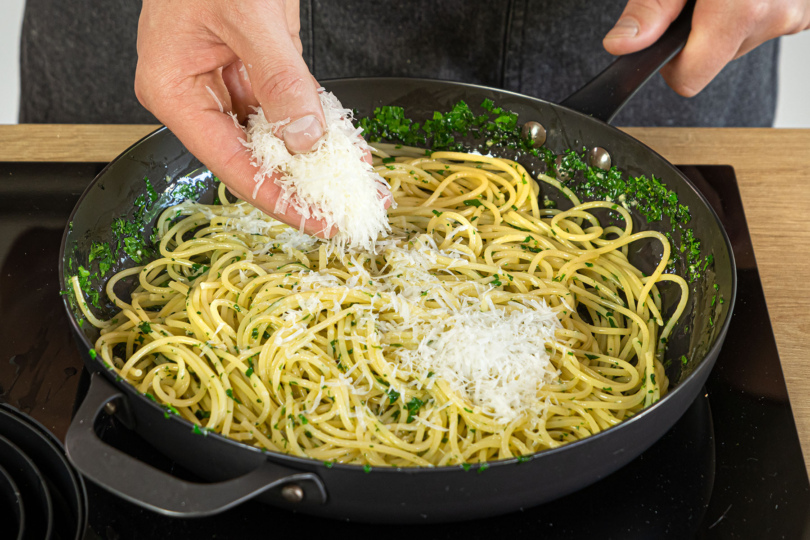 geriebenen Pecorino zu den Spaghetti aglio e olio geben