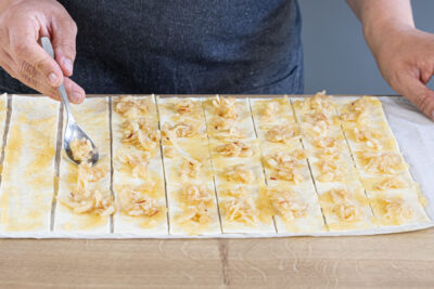 geriebene Äpfel, Mus und Rosinen auf dem Blätterteig verteilen