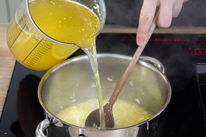 Gemüsebrühe zu den Zwiebelwürfeln gießen