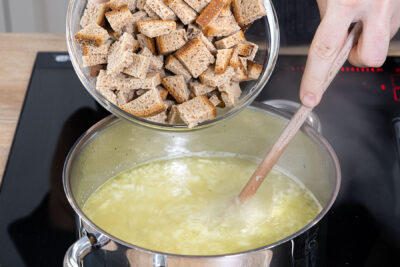 Brotwürfel in die Suppe geben