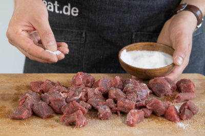 Fleisch für den Gulasch salzen