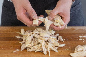 Fleisch für die Hühnersuppe zupfen