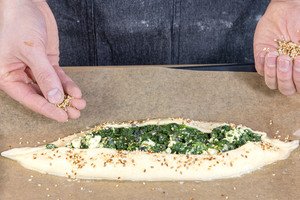 Pide mit Käse-Spinat-Füllung mit Sesam bestreuen