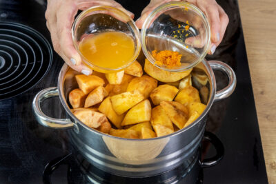 Orangensaft und -abrieb zu den Quittenstücken in den Topf geben