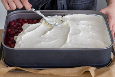 Quarkcreme auf den Kirschen des Spekulatius-Kuchens verteilen