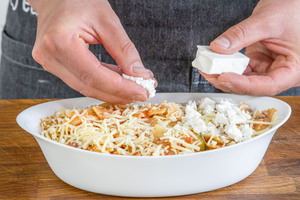 Feta über den vegetarischen Nudelauflauf mit Gemüse bröseln
