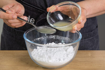 Zitronensaft und Puderzucker in eine Schüssel geben