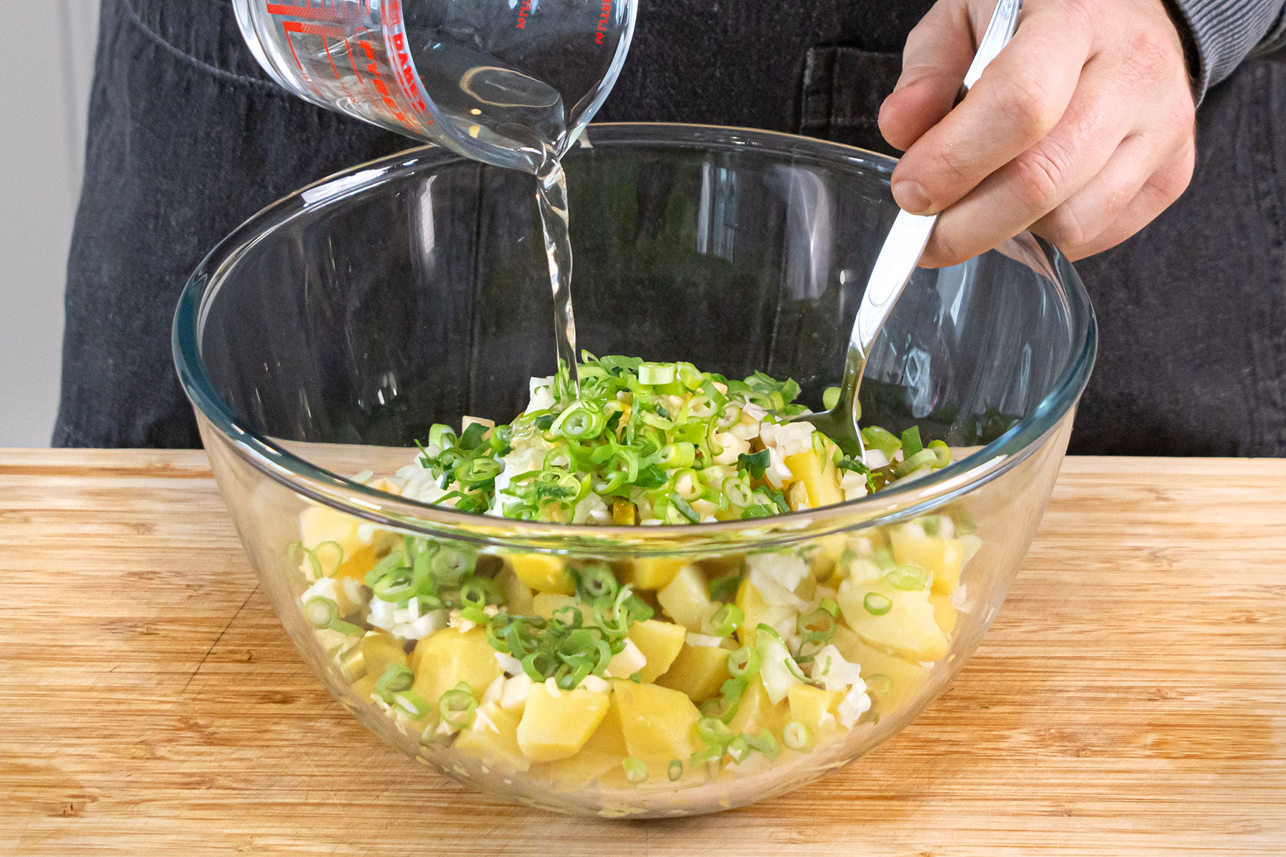 Alle Zutaten zum Kartoffelsalat vermengen
