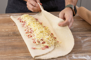 Längsseite mit Speck und Käse belegen