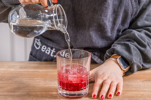 Wasser zum Himbeer-Mojito-Cocktail gießen