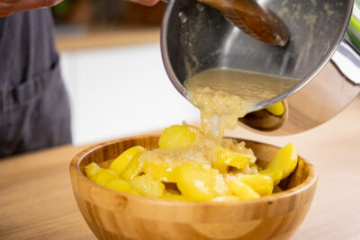 Dressing über den Kartoffelsalat geben