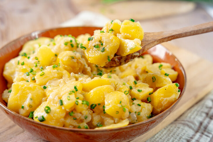 Kartoffelsalat mit Essig und Öl mit dem Löffel nehmen