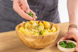 Schnittlauch über den Kartoffelsalat geben