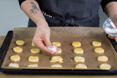 Kokosplätzchen mit Kokosraspeln bestreuen
