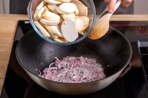 Pilze mit den Zwiebeln in die Pfanne geben