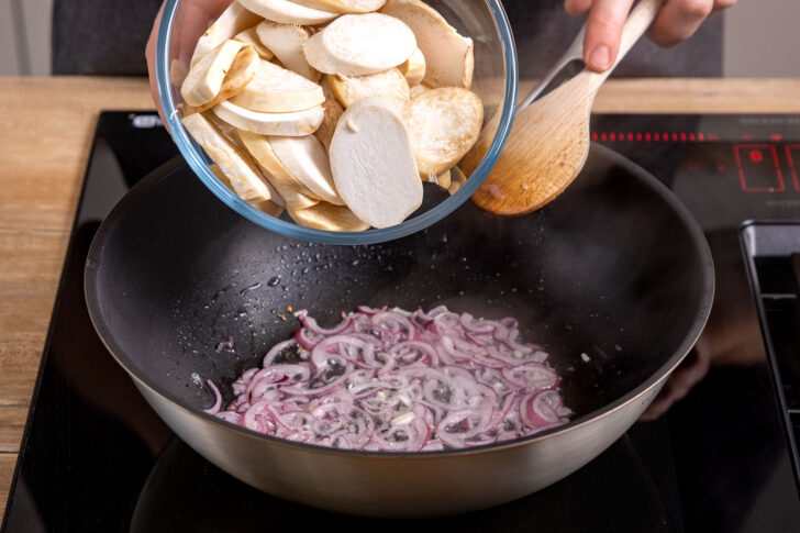 Pilze mit den Zwiebeln in die Pfanne geben