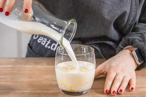 Milch in das Glas gießen