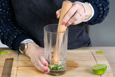 Limetten und Rohrzucker mit dem Stößel zerdrücken