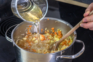 Brühe zum Sauerkrauteintopf geben