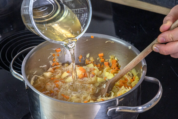 Brühe zum Sauerkrauteintopf geben
