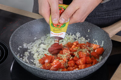 Tomatenmark zum gebratenen Gemüse geben