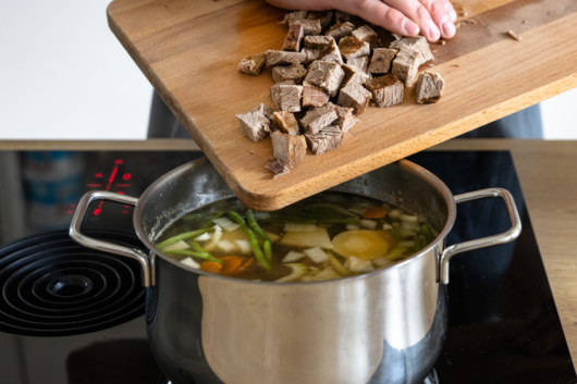 Rindfleisch zu Gemüsesuppe geben