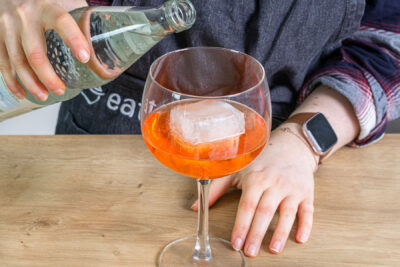 Wasser zum Aperol Spritz Cocktail gießen