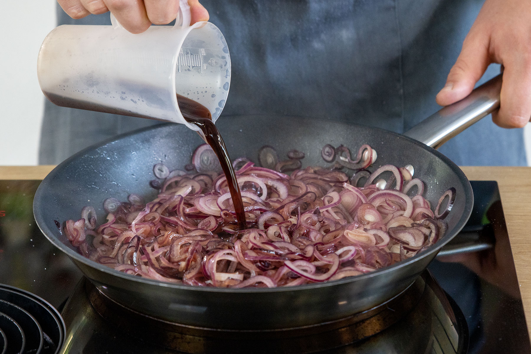 Balsamico zu den Zwiebeln gießen