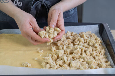 Streusel auf dem Butterstreuselkuchen verteilen