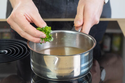 Kräuter in die Frittatensuppe geben