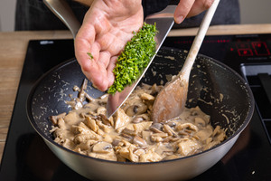 Petersilie zum Hähnchengeschnetzeltem mit frischen Champignons geben