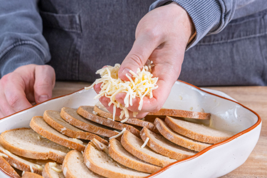 Herzhaften Brotauflauf mit Käse toppen