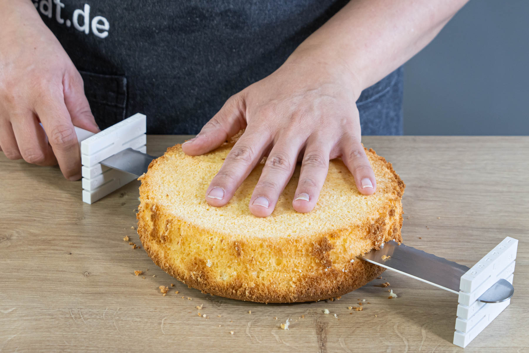 Tortenboden für die Himbeer-Sahne-Torte längs in 2 gleiche Hälften schneiden