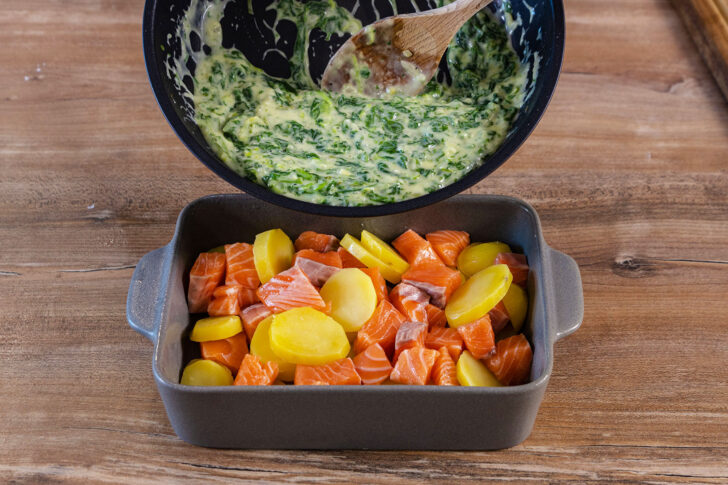 Spinat-Sahne-Soße über Lachs und Kartoffeln geben