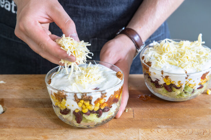 Käse über den Schichtsalat streuen