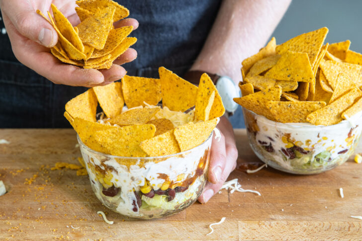Tortilla-Chips auf dem Schichtsalat verteilen