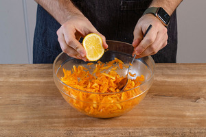 Zitrone an den Möhrensalat mit Apfel geben