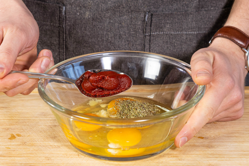 Gewürze und Tomatenmark zum Ei geben