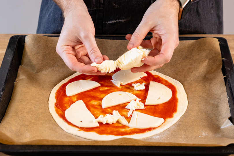 Mozzarella auf Pizza verteilen.